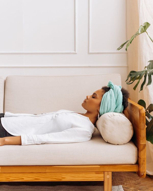 Woman in a calm yoga pose indoors, surrounded by soft light.
